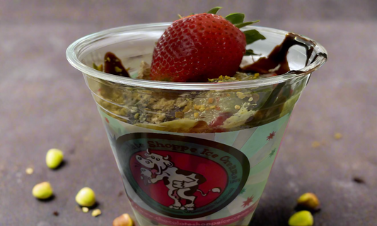 whole strawberries in a cup layered with chocolate, pistachio butter, crunchy kunafa and pistachios