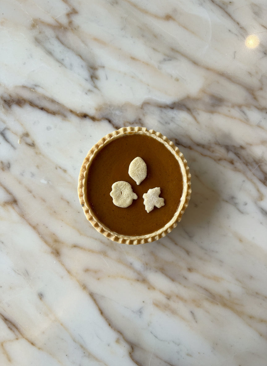 Sweet Pea's award winning 5" pumpkin pie with fall decorations set in an ai generated background