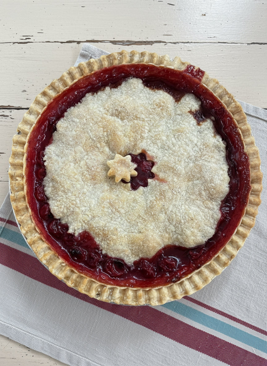 Sweet Pea's 5" cherry pie on a tablecloth with an ai generated background.